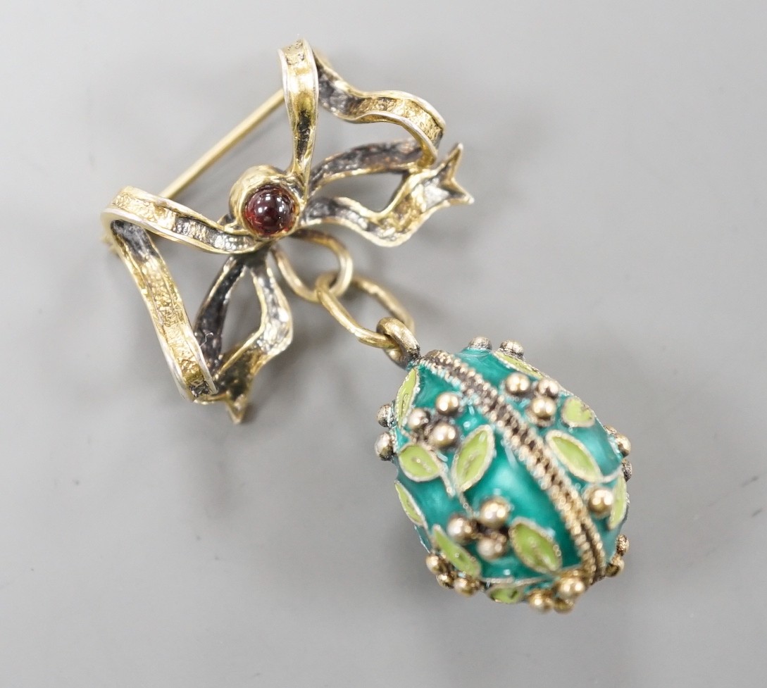 A mid 20th century Soviet gilt 925 and enamelled egg pendant, 21mm, on a gilt white metal ribbon bow suspension brooch.
